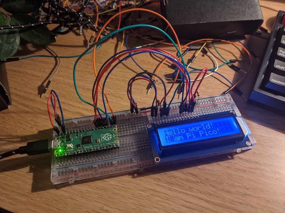A photograph of the HD44780 LCD wired up to a Raspberry Pi Pico on a small breadboard with a mess of jumper wires